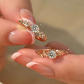 Pavé floral and vine solitaire rings held between fingers in sunlight