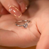 Minimalist open arc ring with a solitaire diamond in a four-prong setting, gently placed on a hand