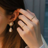 Model wearing pearl earring and two bamboo-texture gold rings, one pavé, one plain