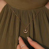 Model wearing GRYKA rose-gold crescent-moon and star diamond necklace over an olive pleated dress