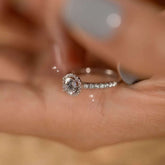 Hand holding halo lab diamond ring with round center stone