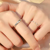 18K white gold couple rings – dainty diamond eternity band for her and classic faceted band for him, close-up on hand.