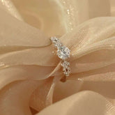 Tapered-cluster diamond engagement ring sparkling on champagne silk fabric