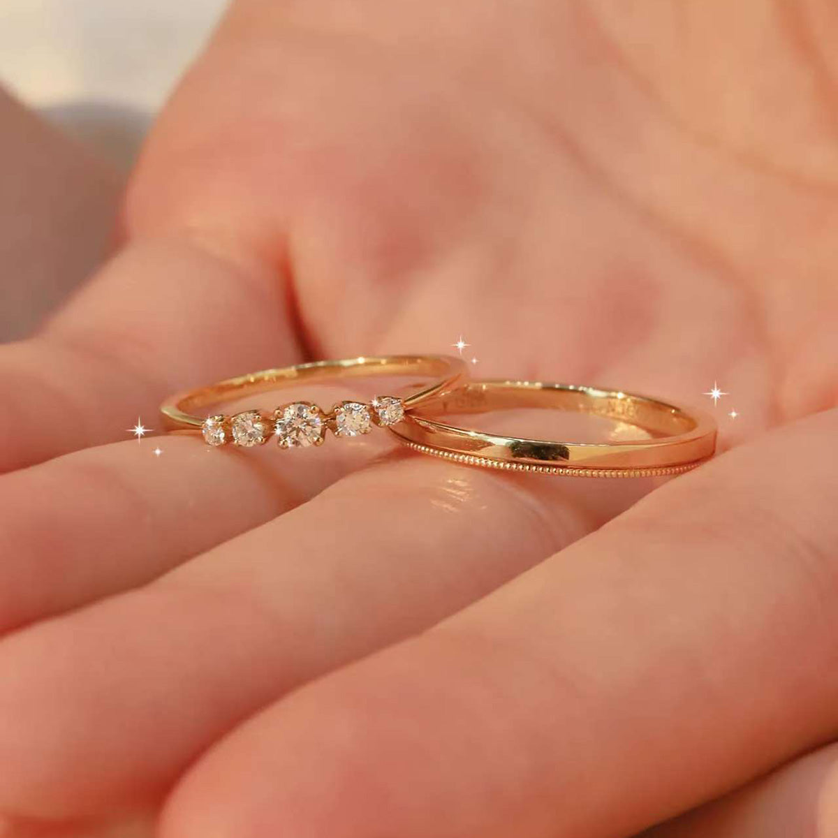 18K gold diamond stacking ring set – five stone diamond band and minimalist plain wedding band on palm
