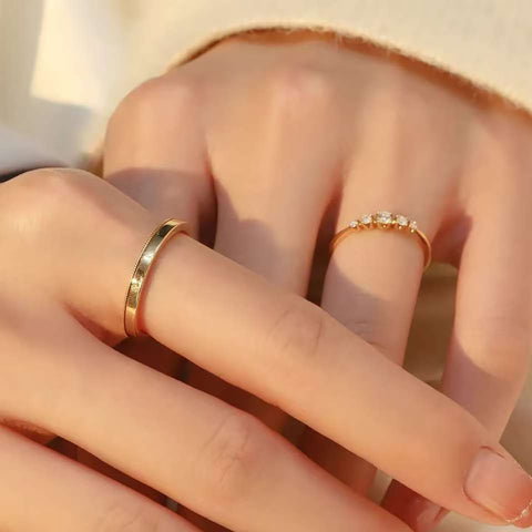 
Woman’s hand wearing 18K gold diamond ring set – elegant five-stone diamond band and polished plain ring