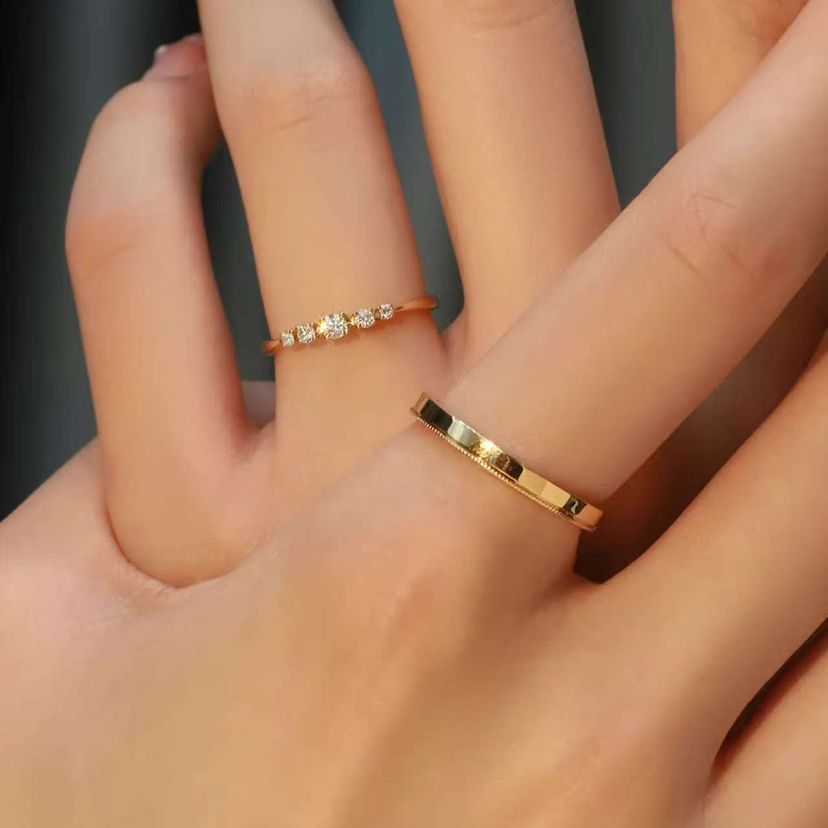 Stacked 18K gold diamond ring and simple gold band on fingers – modern bridal jewelry set