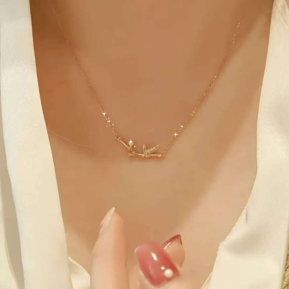 Close-up of 18K gold bamboo pendant with leaf-pavé and single diamond dew