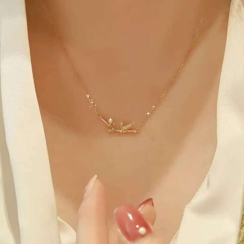 Close-up of 18K gold bamboo pendant with leaf-pavé and single diamond dew