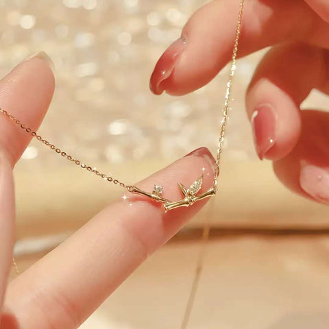 Hand holding bamboo branch necklace against sparkling backdrop