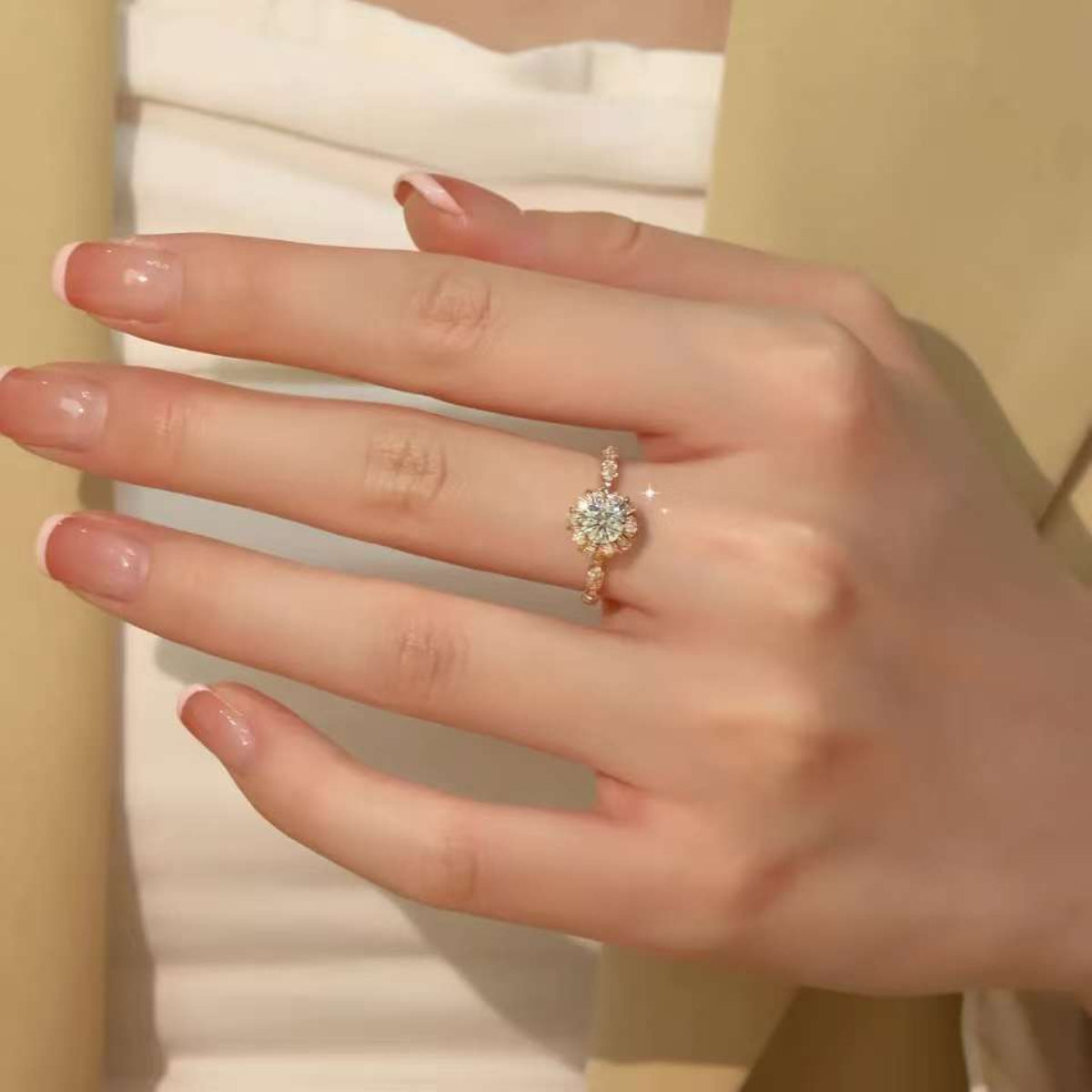 Rose-gold baguette halo diamond ring on hand against beige blazer