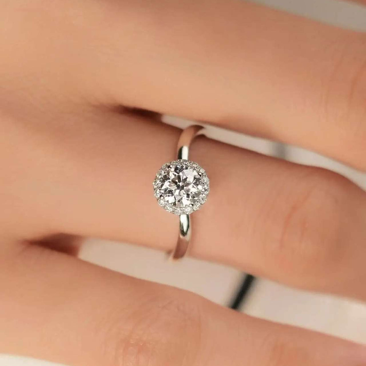 Elegant engagement ring with sparkling diamond halo, worn on finger