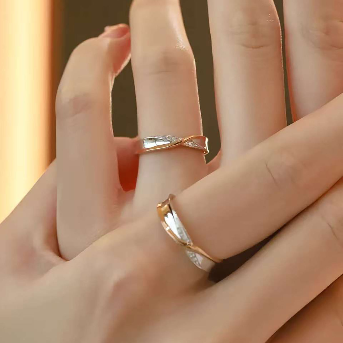Fingers crossing, each adorned with slim two-tone solid gold crossover band