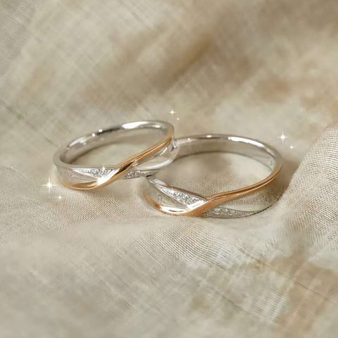 Pair of intertwined solid gold promise rings resting on neutral linen fabric