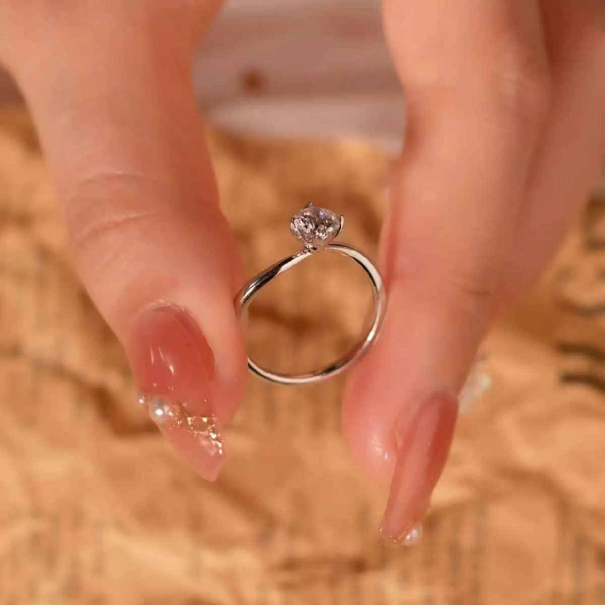 Artistic bypass solitaire ring held between fingers, showing the elegant curved band