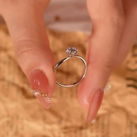 Artistic bypass solitaire ring held between fingers, showing the elegant curved band