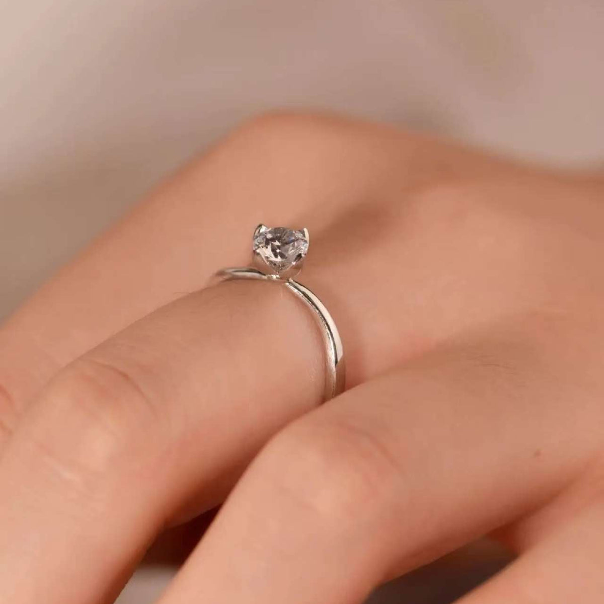 Close-up of arc-shaped solitaire ring on finger, reflecting minimalist elegance