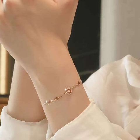 Minimalist moon-and-stars gold bracelet styled on wrist
