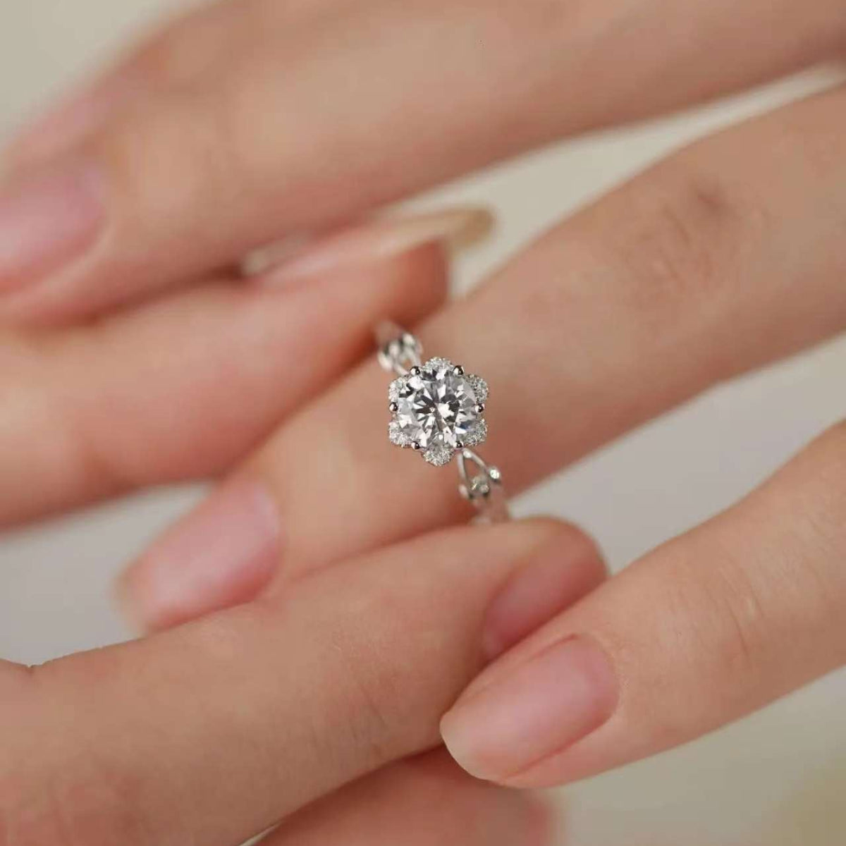 Delicate floral solitaire engagement ring worn on hand, showing the sparkling round center stone.