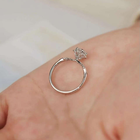 Close-up of the floral six-prong diamond ring placed on palm, highlighting the flower-shaped setting.