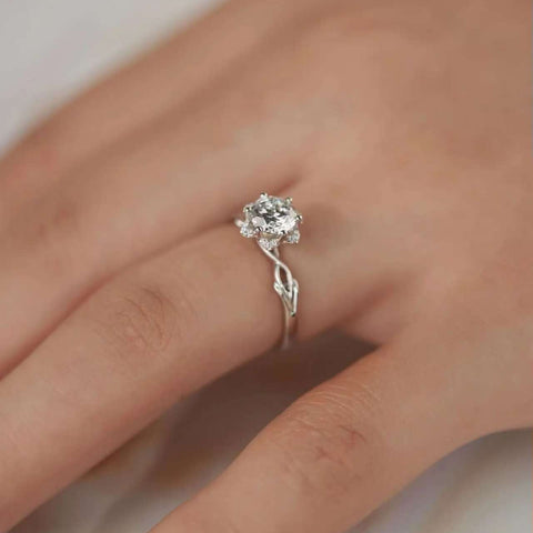 Elegant flower-inspired engagement ring on finger, highlighting slender branch-shaped shank.