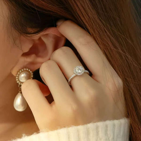 Halo engagement ring worn with pearl drop earring for elegant styling
