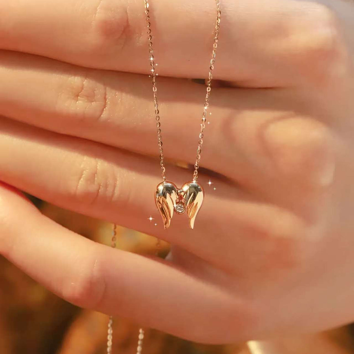 Close-up of 18K gold angel-wings heart necklace with sparkling lab diamond