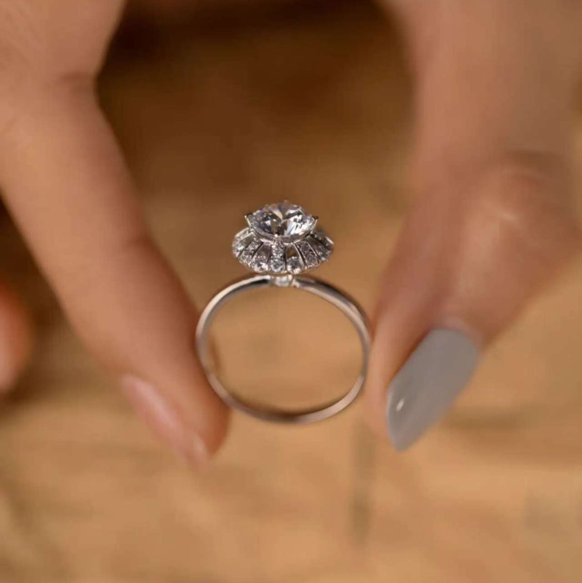 
Hand holding ballerina halo ring, focus on Art-Deco crown detail