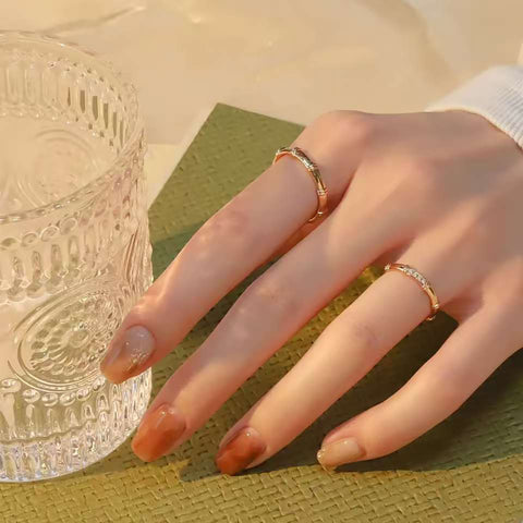 Hand holding ribbed glass, showing stackable bamboo gold rings in sunset light