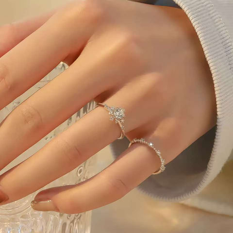 Hand wearing floral halo solitaire ring stacked with pavé contour band while holding crystal glass