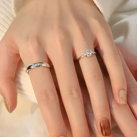 Close-up view of diamond bridal set on hand, sparkling center stone engagement ring and classic men’s wedding band in white gold.