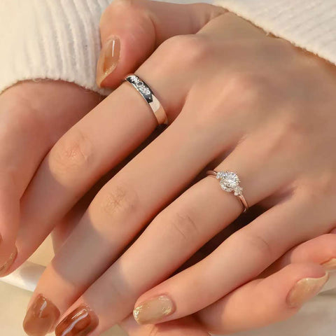 Modern bridal ring set for couples, center stone diamond ring and sleek engraved band, showcased on hands.