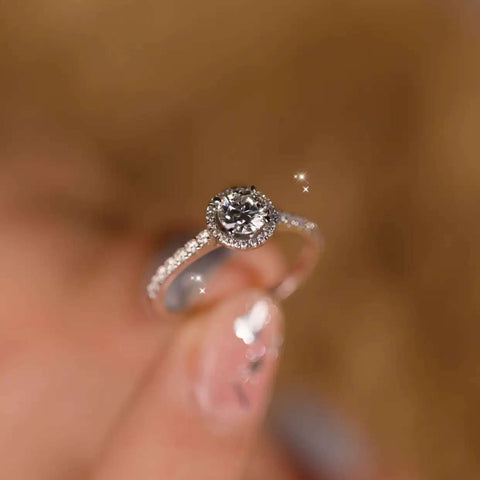 Close-up of sparkling halo engagement ring in hand