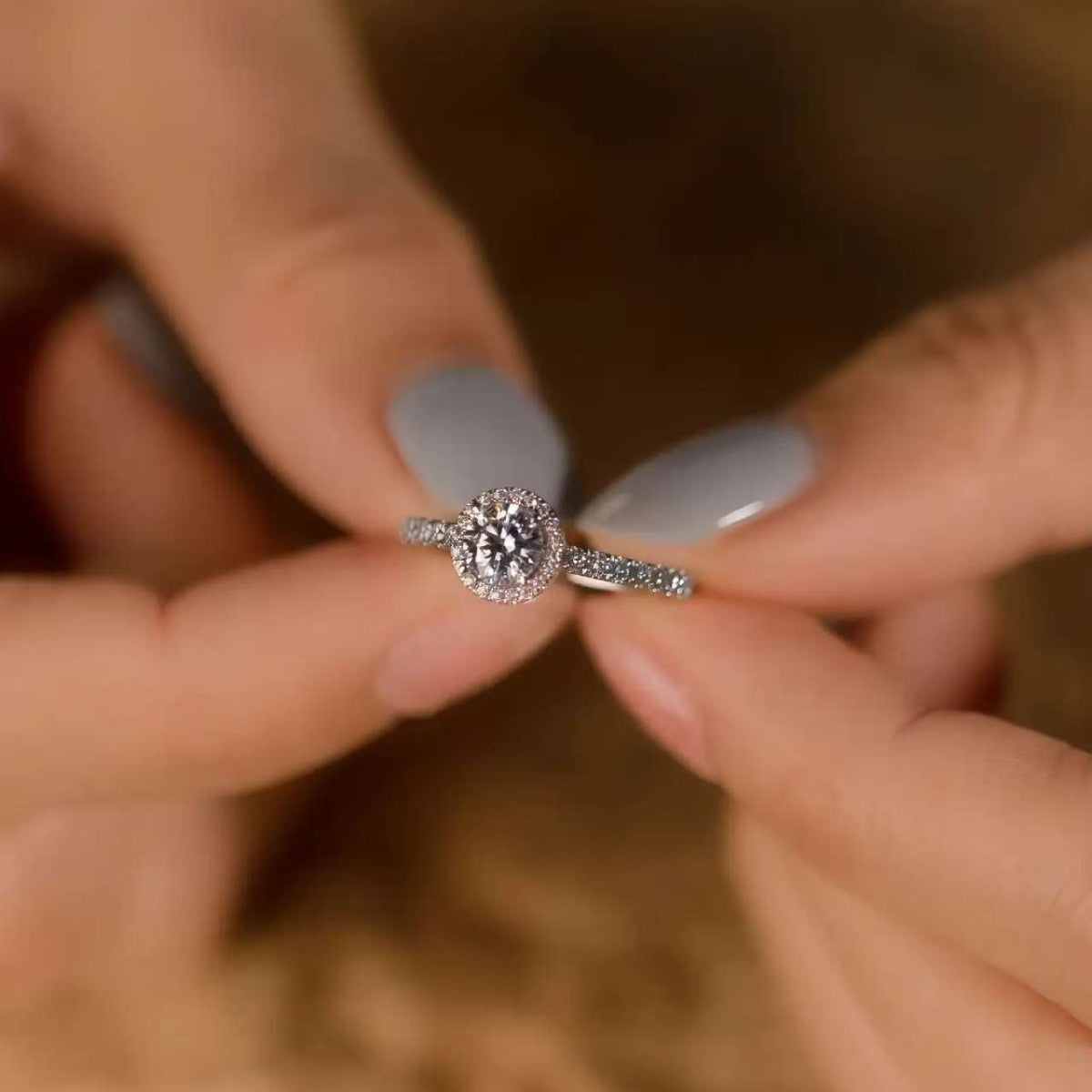 Elegant halo diamond ring held by both hands, French pave band