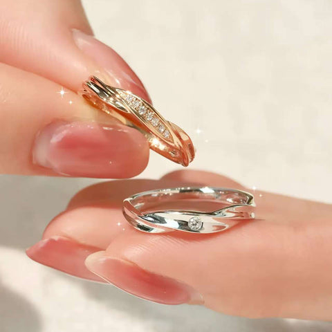 Hand holding rose gold and white gold crossover couple rings, pavé and single diamond details
