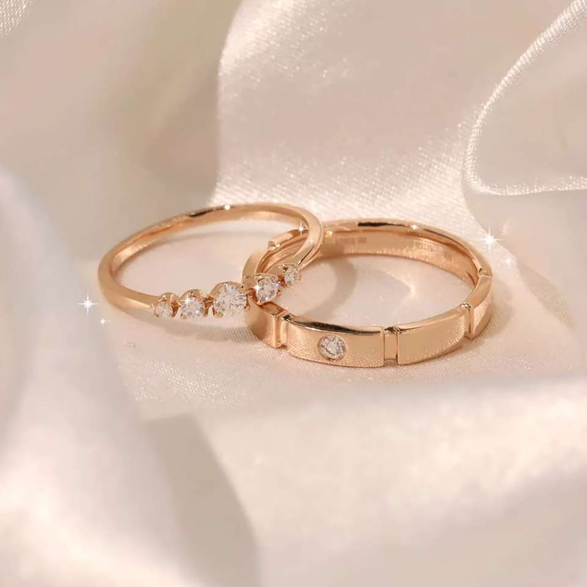 Pair of rose-gold rings—half-eternity five-diamond band beside brushed bezel band on satin