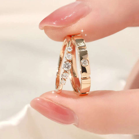 Close-up of rose-gold slim five-diamond ring next to brushed bezel band held between fingers