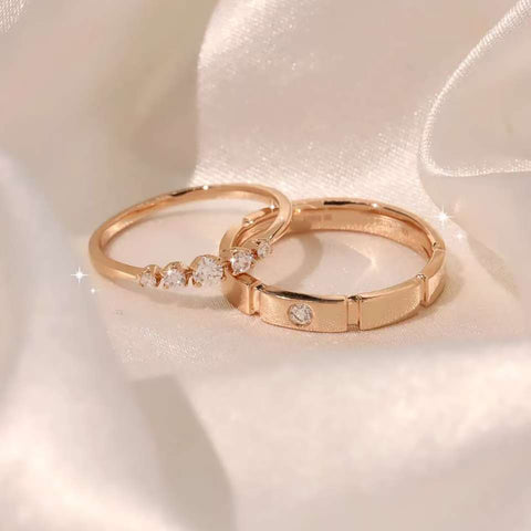 Pair of rose-gold rings—half-eternity five-diamond band beside brushed bezel band on satin