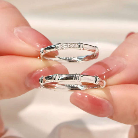 Close-up of fingers holding pavé bamboo ring and plain bamboo ring in white gold
