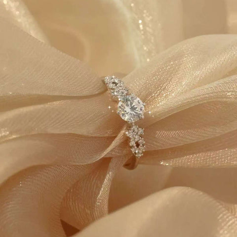 Tapered-cluster diamond engagement ring sparkling on champagne silk fabric