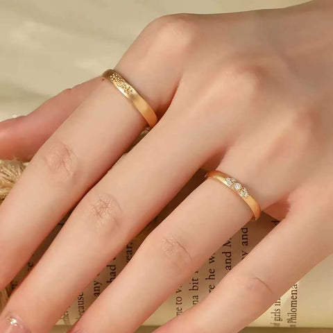 Hand wearing matte sunburst gold ring and trio-diamond gold ring on adjacent fingers