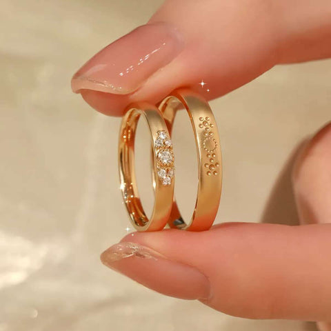 Fingertips holding trio-diamond band and sunburst engraved band side-by-side